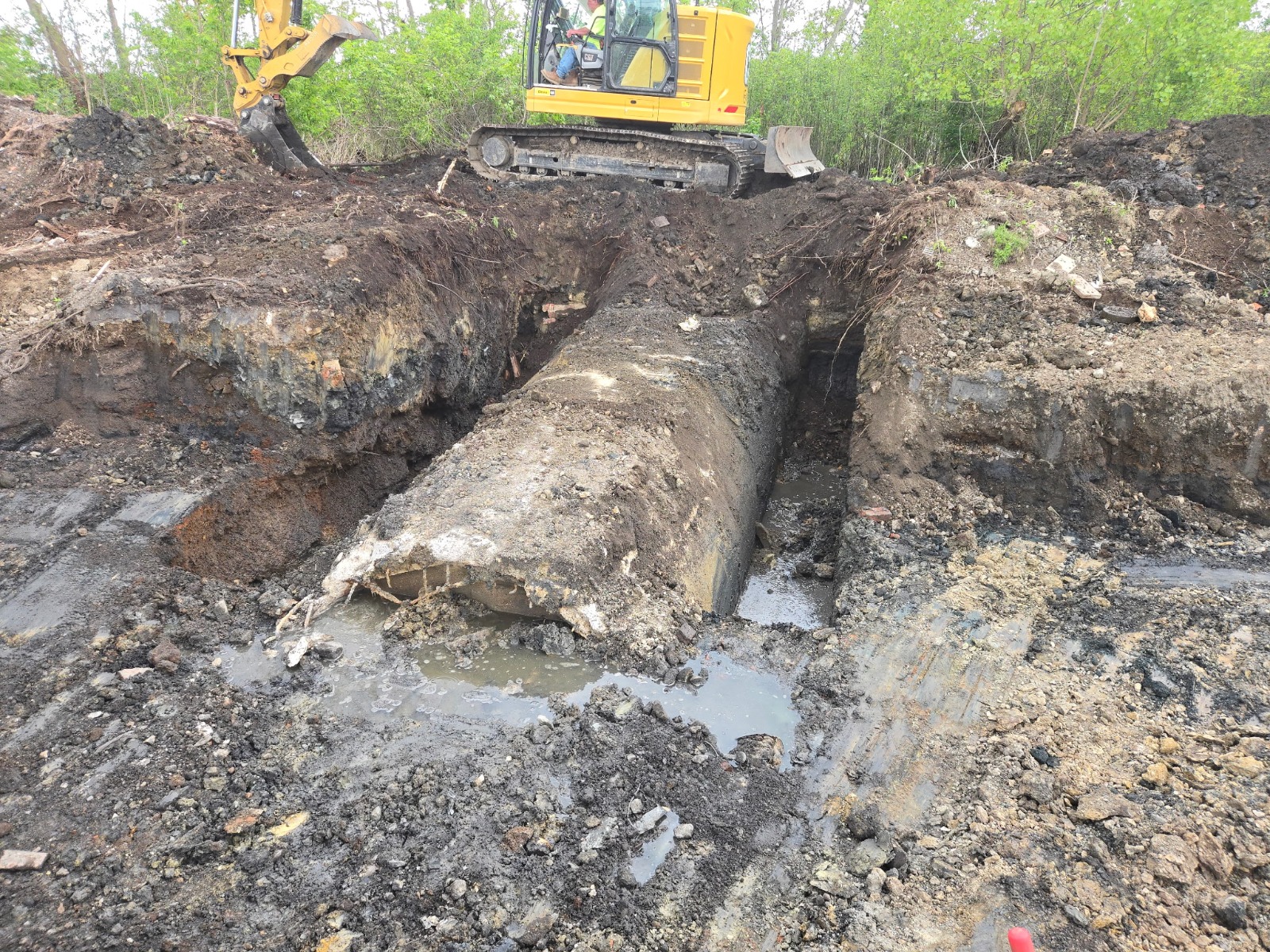 large buried structure exposed in the excavation, with water pooling